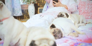 一个女人和她的宠物狗坐在床上玩智能手机。