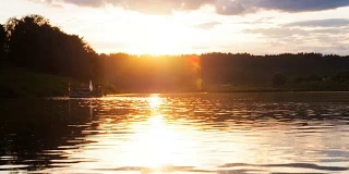 活跃的人们在小木筏上玩得很开心。日落时分，队员们在河面上一个临时制作的木筏上划桨