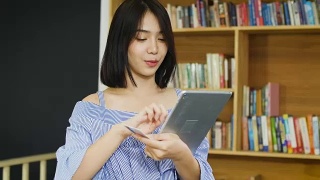 年轻的亚洲美女在家里使用数码平板电脑视频素材模板下载