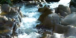 在山区湍急的河流中，小溪的水流近距离。水流在岩石密布的河里迅速流动。山河中水流湍急