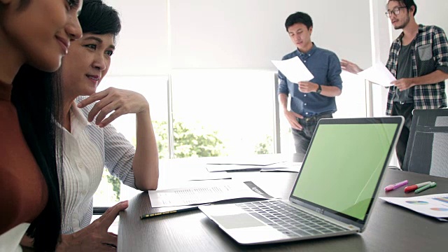 商务人士在会议室用绿屏笔记本电脑召开视频会议。