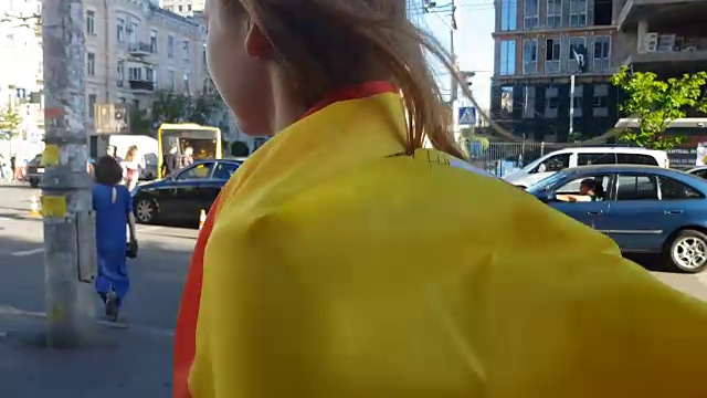 美丽的女孩包裹在西班牙国旗走过城市，拉拉队的特写镜头