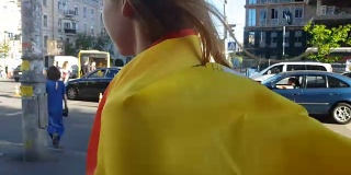 美丽的女孩包裹在西班牙国旗走过城市，拉拉队的特写镜头