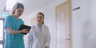 在医院里，忙碌的医生一边聊天，一边用平板电脑在大楼里走动。新型现代化、功能齐全的医疗设施。