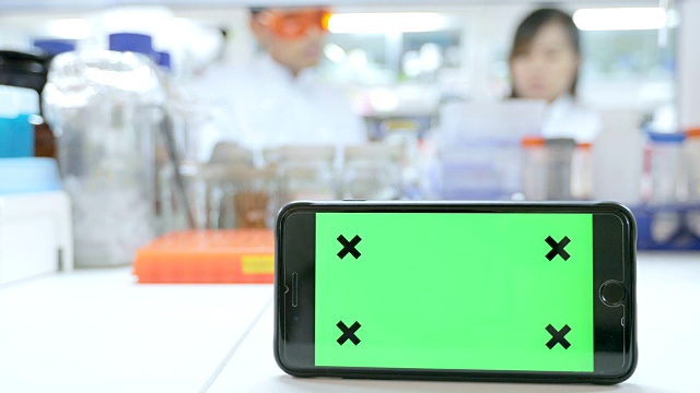 智能手机绿色屏幕背景与科学家在实验室工作