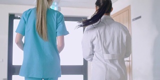 在医院，护士和医生走过走廊的背影照片。医院工作人员。