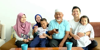 一个马来西亚家庭坐在沙发上看电视