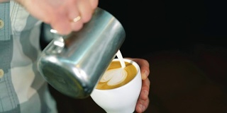 咖啡师将牛奶倒入咖啡杯中，制作拉花艺术。慢动作镜头。