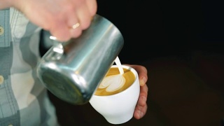 咖啡师将牛奶倒入咖啡杯中，制作拉花艺术。慢动作镜头。视频素材模板下载