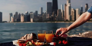 食物特写:水果和果汁在密歇根湖在芝加哥，美国。女人把一颗草莓放在盘子里