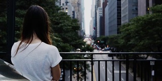年轻美丽的女人站在桥上看交通道路在纽约，美国