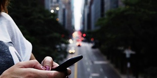 在美国纽约的一座桥上，女性手握手机的特写镜头