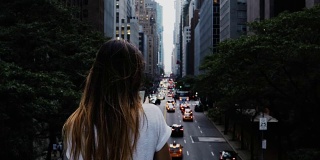 年轻时尚的女人站在桥上看交通道路在纽约市中心，美国
