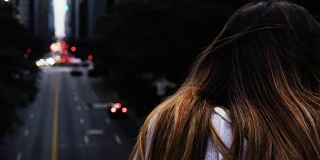 近距离观看年轻的黑发女性站在桥上，看着交通道路在纽约，美国