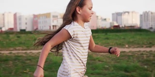 夏日里，有趣的小女孩在城市草坪上奔跑