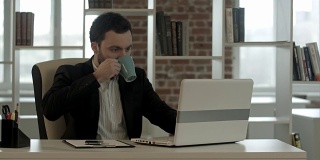 一个商人一边在办公室里用电脑打字一边工作