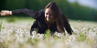 年轻快乐的女人在阳光明媚的日子里在蒲公英的田野里玩耍
