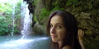 模特在美丽的热带瀑布附近摆姿势拍照。慢动作