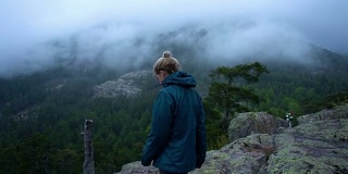 在云天的慢镜头中，年轻女子站在山上的视点上