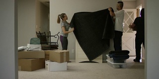 女人和男人用移动的毯子覆盖家具