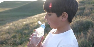 夕阳下，男孩正在喝塑料瓶里的水