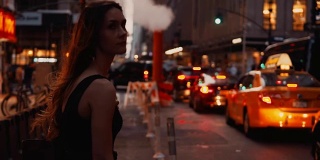 年轻美丽的女人站在靠近美国纽约的交通道路上的烟筒，等待出租车