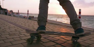 近距离拍摄的年轻人滑板在道路附近的大海，慢动作