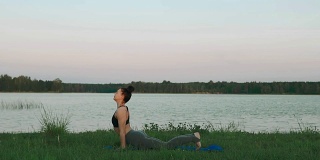 年轻女子做瑜伽在早上的蓝色瑜伽垫在安静的风景
