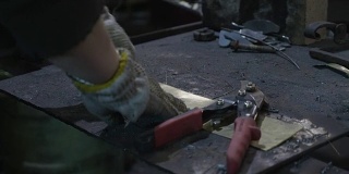 女铁匠在她的车间里用钢丝切割机切割一块铝