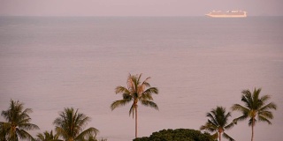 邮轮暑期度假概念。游轮在遥远的海面上靠近日出时的热带岛屿