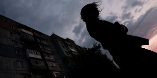 一个女孩的剪影在公寓楼的背景下。深刻的情感创伤和经历。
