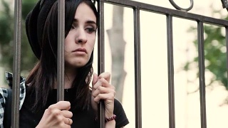 一个悲伤绝望的女孩透过栅栏望着，叹息着视频素材模板下载