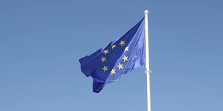 慢镜头欧盟旗帜在白旗杆上升起，迎风飘扬