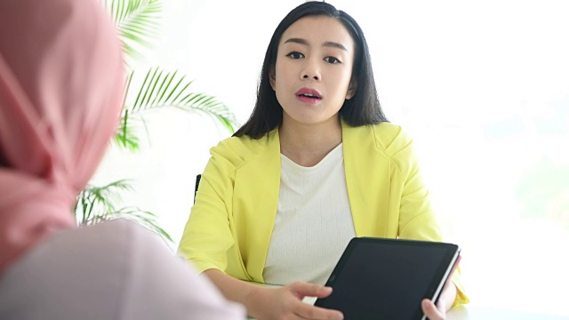 年轻的中国女商人正在用平板电脑开会