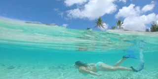 半水下:年轻女子浮潜在令人窒息的水晶般清澈的水中。