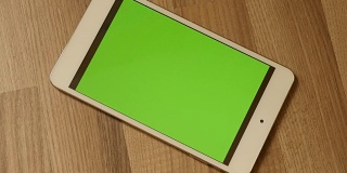 放大到木地板上的绿色屏幕平板电脑