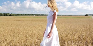 微笑的年轻女子在白色的裙子在谷物地里