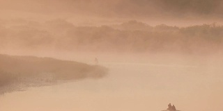 宁静的湖，河和人在古老的木船上钓鱼在美丽的薄雾日出在夏天的早晨。渔夫在船上。俄罗斯自然