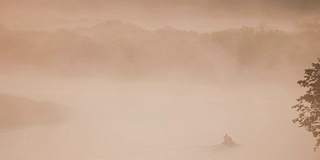 宁静的湖，河和人在古老的木船上钓鱼在美丽的薄雾日出在夏天的早晨。渔夫在船上。俄罗斯自然