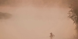 宁静的湖，河和人在古老的木船上钓鱼在美丽的薄雾日出在夏天的早晨。渔夫在木船上。俄罗斯自然