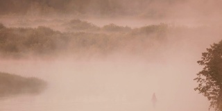 宁静的湖，河和人在古老的木船上钓鱼在美丽的薄雾日出在夏天的早晨。渔夫在木船上。俄罗斯自然