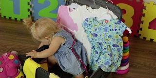 一个孩子和一个装衣服的手提箱。孩子是观光客，旅行和度假。