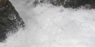 山河中湍急的小溪。干净的水上升起泡沫。一股带有近距离浪花的暴风雨般的激流。慢动作视频
