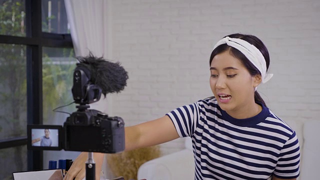 年轻的亚洲美容博主介绍化妆品和记录她的化妆教程视频到社交网络在家通过互联网