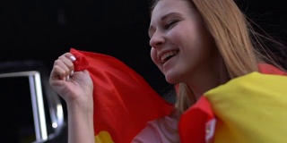 快乐的女孩支持西班牙足球队，亲吻国旗庆祝胜利
