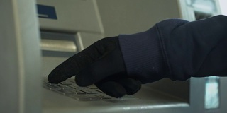 戴着手套的可疑男子插入密码，从银行账户偷钱