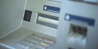 女性银行客户在自动取款机上查看账户余额并取回她的银行卡