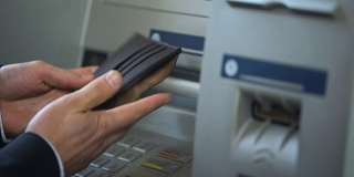 一名男子数着从ATM中取出的俄罗斯卢布，把现金放进钱包，旅行