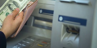 数着从ATM取的美元，把现金放进钱包，轻松的银行业务