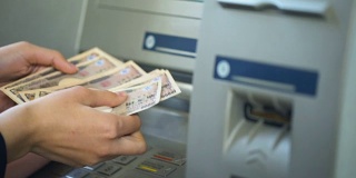 女性清点从ATM中取出的日元，把现金放入钱包，旅游